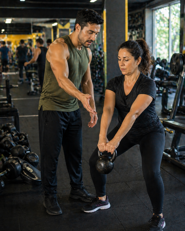Personal trainer ajudando aluna em academia
